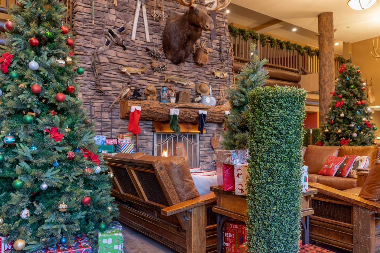 The Grand Hotel At The Grand Canyon Tusayan Ngoại thất bức ảnh The photo shows a cozy holiday scene with a rustic aesthetic. In the center, there is a wooden bench in front of a stone fireplace, which is adorned with festive decorations. Above the fireplace, a mounted moose head adds a touch of wilderness charm.