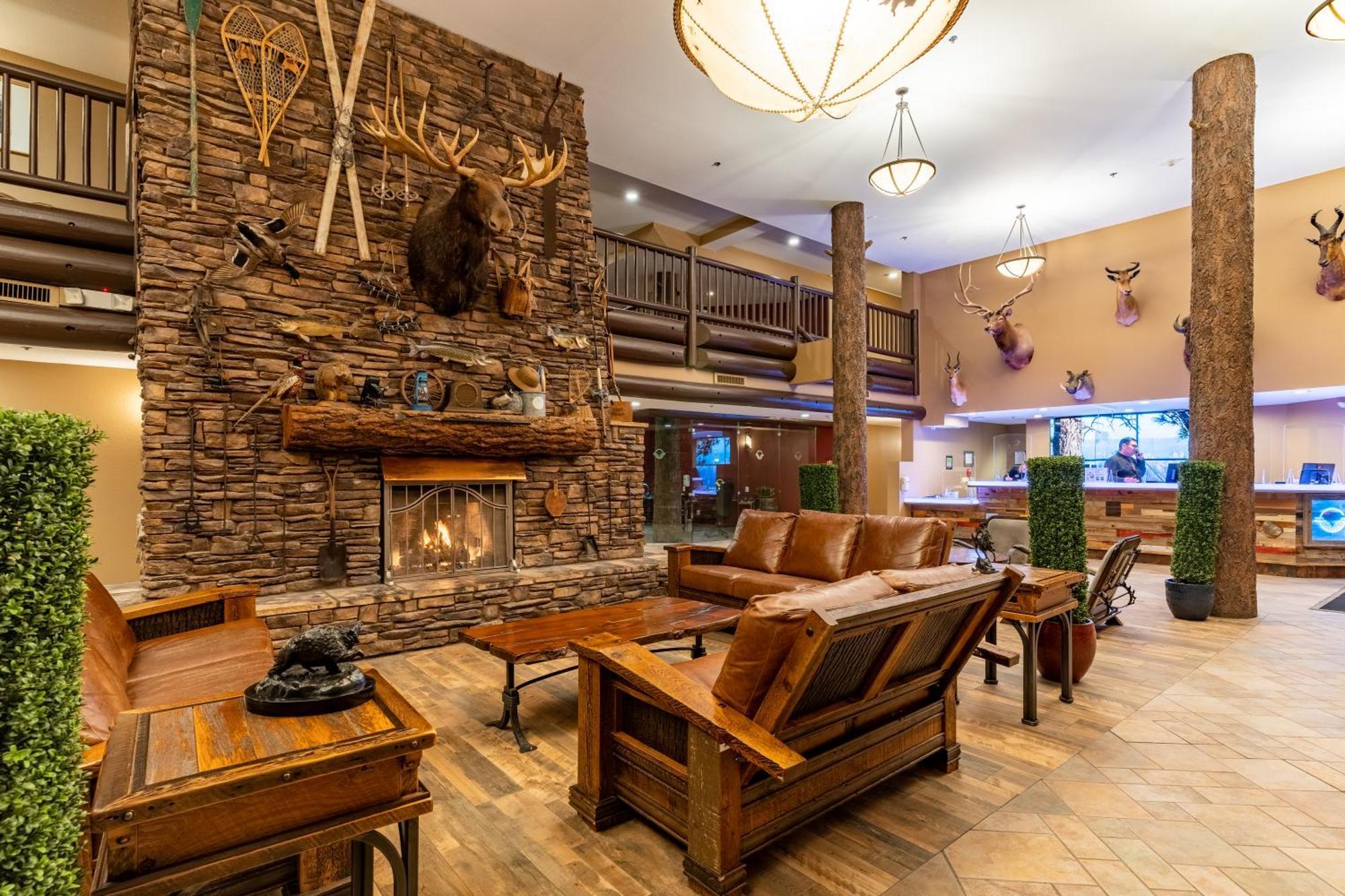 The Grand Hotel At The Grand Canyon Tusayan Ngoại thất bức ảnh The photo shows a cozy lobby area with a rustic design. A large stone fireplace is the focal point, adorned with a mounted animal head and various decorative items like snowshoes and antlers. The seating consists of wooden furniture, including a coup